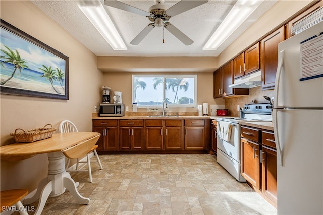 4549 SE 5th Pl Unit 109, Cape Coral, FL 33904 - kitchen with white appliances, light countertops, light stone finish floors, under cabinet range hood, and brown cabinets