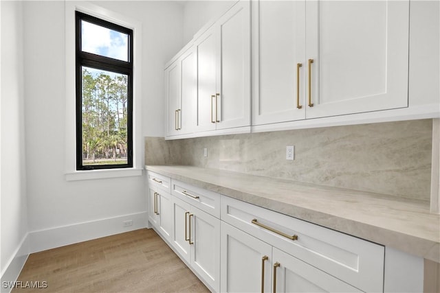 5174 Sycamore Dr, Naples, FL 34119 - kitchen featuring white cabinets, light wood-type flooring, light stone counters, and decorative backsplash