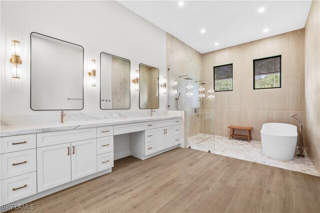 5174 Sycamore Dr, Naples, FL 34119 - bathroom with walk in shower, double vanity, a freestanding tub, wood finished floors, and recessed lighting