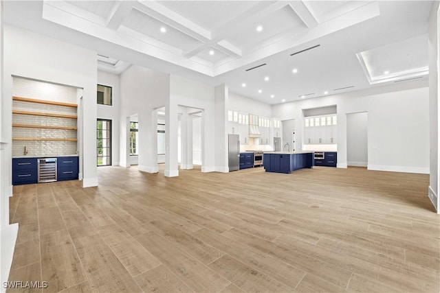 5174 Sycamore Dr, Naples, FL 34119 - unfurnished living room featuring light wood-style floors, a high ceiling, bar, beamed ceiling, and beverage cooler