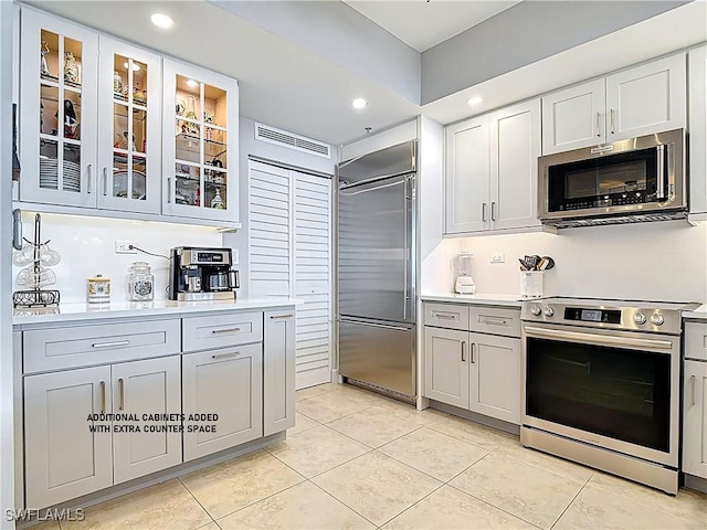 3000 Oasis Grand Blvd Unit 1203, Fort Myers, FL 33916 - kitchen with stainless steel appliances, light tile patterned flooring, light countertops, glass insert cabinets, and recessed lighting