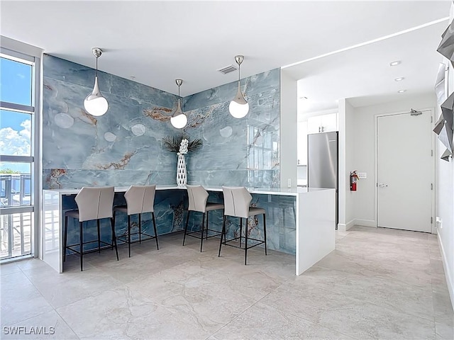3000 Oasis Grand Blvd Unit 1203, Fort Myers, FL 33916 - bar with stainless steel refrigerator, decorative light fixtures, and light marble finish floors