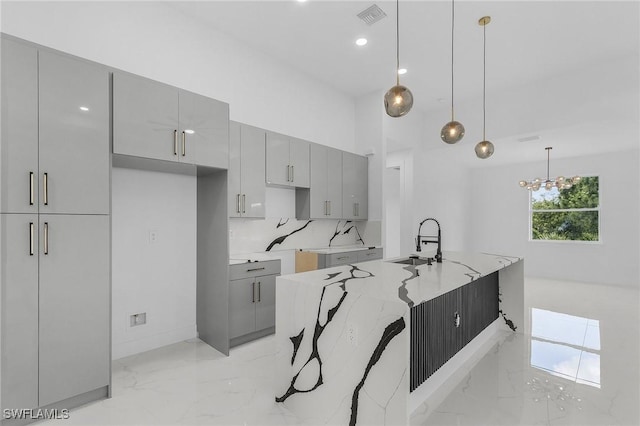 3805 E 16th St, Lehigh Acres, FL 33972 - kitchen with gray cabinets, light marble finish flooring, a high ceiling, decorative light fixtures, and a kitchen island with sink