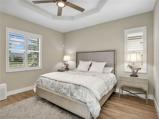 8612 Ibis Cove Cir, Naples, FL 34119 - bedroom with a tray ceiling, wood finished floors, and ceiling fan