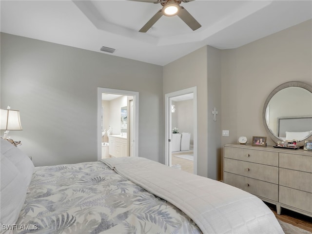 8612 Ibis Cove Cir, Naples, FL 34119 - bedroom featuring a raised ceiling, ensuite bathroom, wood finished floors, and ceiling fan