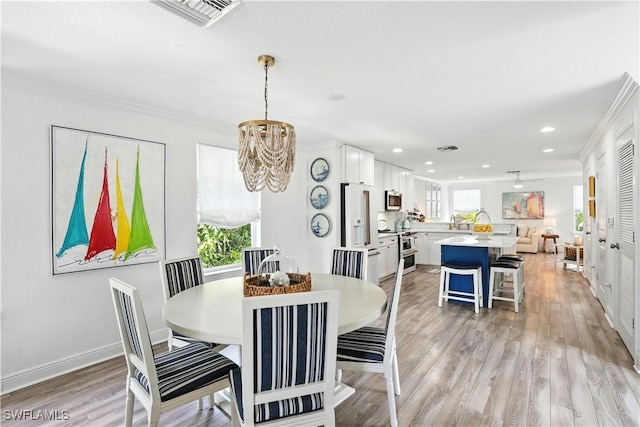 719 Park Ave, Naples, FL 34110 - dining area featuring a chandelier, recessed lighting, crown molding, and light wood-style floors