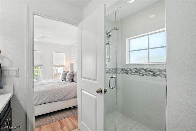 719 Park Ave, Naples, FL 34110 - ensuite bathroom with healthy amount of natural light, a stall shower, vanity, a textured wall, and wood finished floors