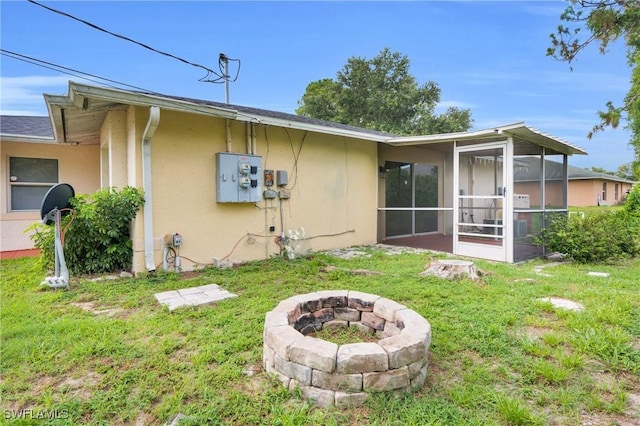 4508/4510 30th St SW, Lehigh Acres, FL 33973 - back of property featuring an outdoor fire pit, stucco siding, a sunroom, and a lawn