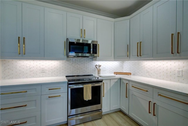 28601 Firenze Way Unit 102, Bonita Springs, FL 34135 - kitchen with appliances with stainless steel finishes, light countertops, decorative backsplash, and light wood-type flooring