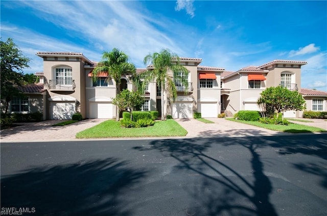 28601 Firenze Way Unit 102, Bonita Springs, FL 34135 - mediterranean / spanish-style home with decorative driveway, stucco siding, a garage, and a balcony