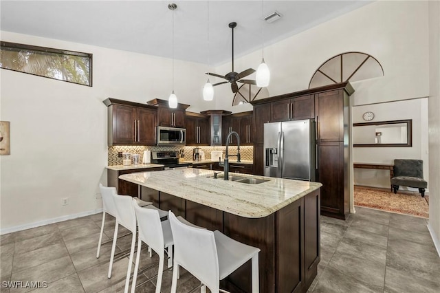 17971 Bermuda Dunes Dr, Fort Myers, FL 33967 - kitchen featuring stainless steel appliances, dark brown cabinets, tasteful backsplash, an island with sink, and pendant lighting
