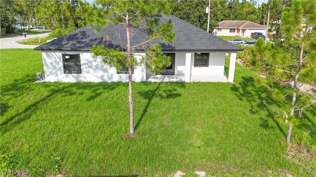 1803 Venice Ave N, Lehigh Acres, FL 33971 - back of property featuring roof with shingles, stucco siding, a yard, and a patio area