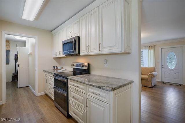 559 Woodruff St, North Fort Myers, FL 33903 - kitchen with stainless steel appliances, light wood-type flooring, white cabinetry, light stone countertops, and electric panel