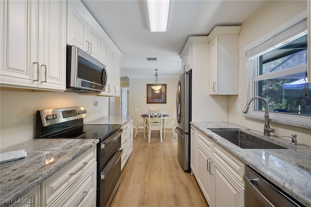 559 Woodruff St, North Fort Myers, FL 33903 - kitchen with stainless steel appliances, white cabinetry, light wood-type flooring, crown molding, and light stone countertops
