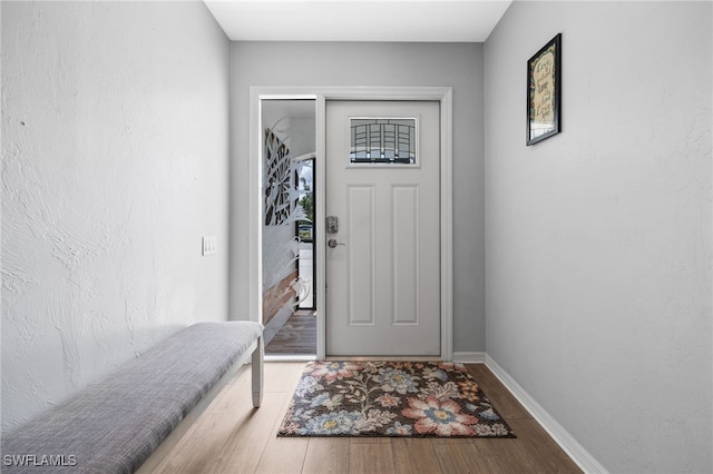 doorway to outside with wood finished floors and baseboards