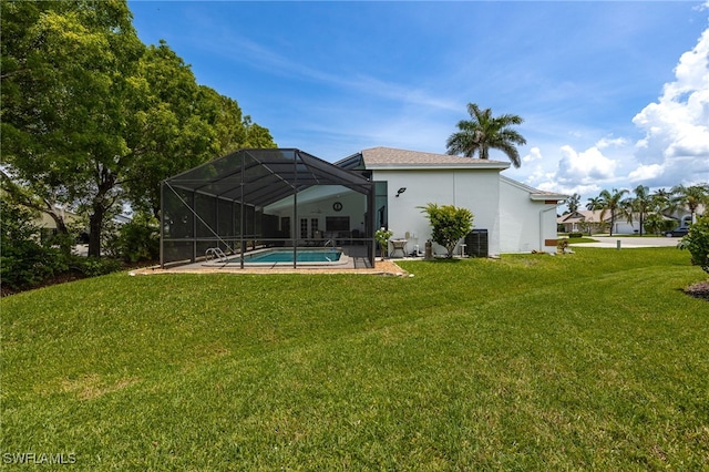 rear view of house with stucco siding, a lawn, an outdoor pool, and glass enclosure