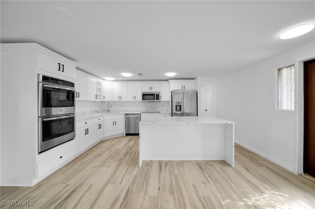3307 Pinetree St, Port Charlotte, FL 33952 - kitchen featuring appliances with stainless steel finishes, light wood-type flooring, a center island, white cabinets, and light stone countertops