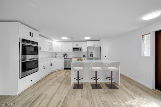 3307 Pinetree St, Port Charlotte, FL 33952 - kitchen with appliances with stainless steel finishes, light countertops, a breakfast bar, light wood-style floors, and a kitchen island