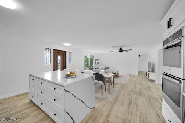 3307 Pinetree St, Port Charlotte, FL 33952 - kitchen with double oven, a ceiling fan, white cabinetry, light wood-style flooring, and open floor plan