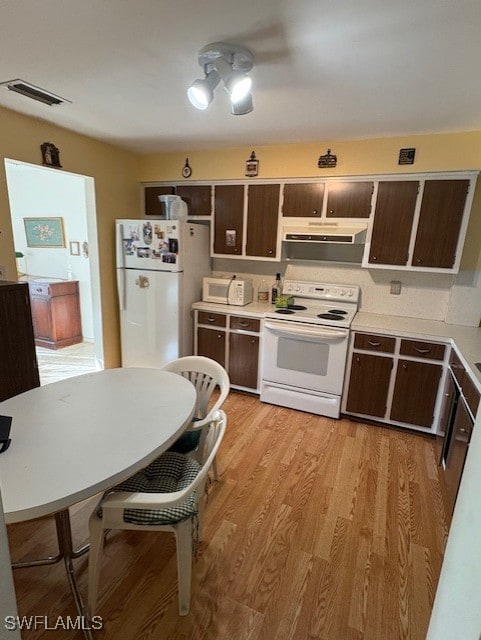 4425 N Atlantic Cir, North Fort Myers, FL 33903 - kitchen with white appliances, range hood, light countertops, and dark brown cabinetry