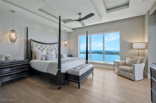 bedroom with light wood-type flooring, a water view, and ceiling fan