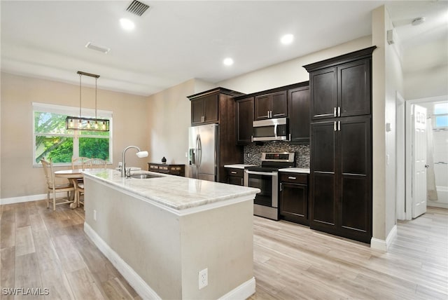 3271 Lemon Ln, Naples, FL 34120 - kitchen with stainless steel appliances, tasteful backsplash, light wood-style flooring, an island with sink, and hanging light fixtures