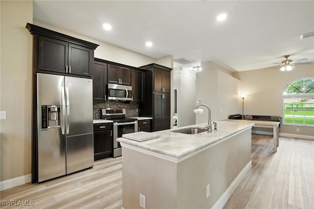 3271 Lemon Ln, Naples, FL 34120 - kitchen featuring stainless steel appliances, light wood-type flooring, backsplash, ceiling fan, and a kitchen island with sink