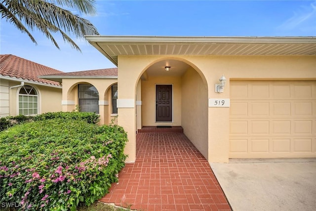 519 99th Ave N, Naples, FL 34108 - doorway to property featuring stucco siding and an attached garage