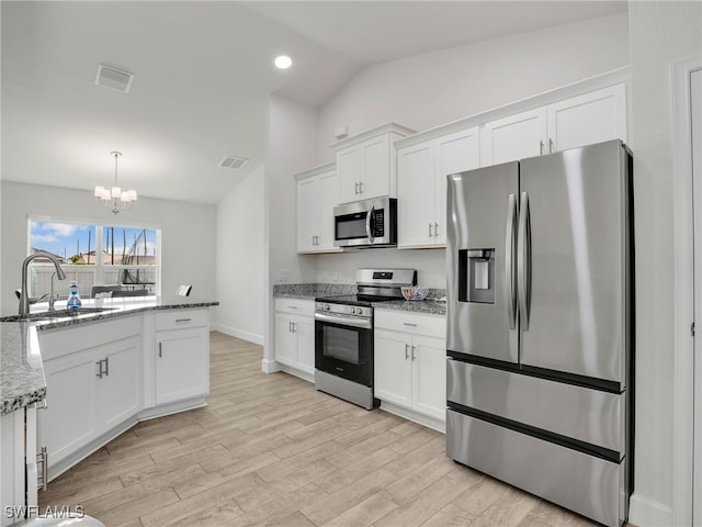 2405 Nelson Rd N, Cape Coral, FL 33993 - kitchen with stainless steel appliances, vaulted ceiling, a chandelier, white cabinetry, and light wood-style flooring