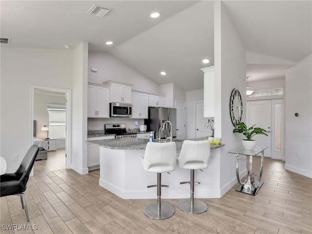 2405 Nelson Rd N, Cape Coral, FL 33993 - kitchen with appliances with stainless steel finishes, light wood-type flooring, a peninsula, a breakfast bar, and white cabinetry