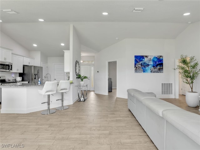 2405 Nelson Rd N, Cape Coral, FL 33993 - living room featuring lofted ceiling, light wood-style flooring, and recessed lighting