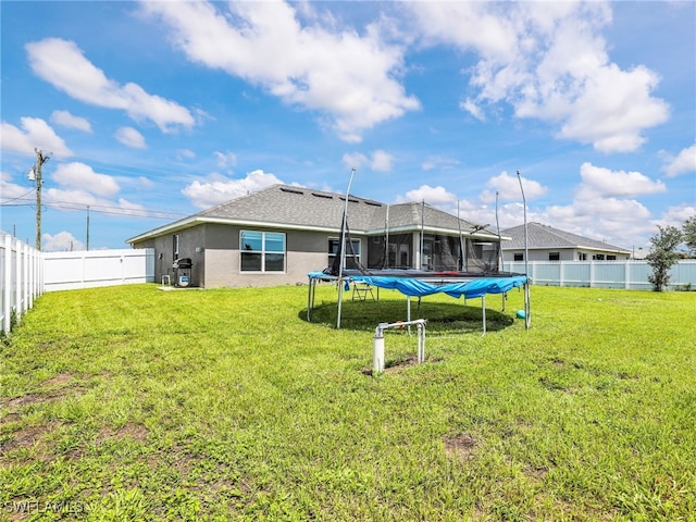 2405 Nelson Rd N, Cape Coral, FL 33993 - rear view of house featuring a trampoline, stucco siding, and a fenced backyard