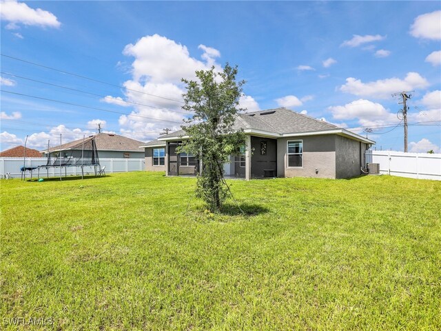 2405 Nelson Rd N, Cape Coral, FL 33993 - back of property with a trampoline, a fenced backyard, stucco siding, and roof with shingles