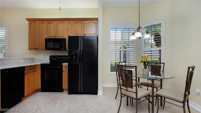 20029 Saraceno Dr, Estero, FL 33928 - kitchen featuring black appliances, light countertops, light tile patterned flooring, brown cabinetry, and decorative light fixtures