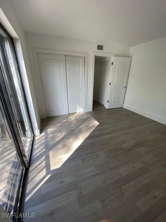 17989 San Juan Ct Unit 3, Fort Myers, FL 33967 - unfurnished bedroom featuring dark wood-style floors, multiple windows, and a closet