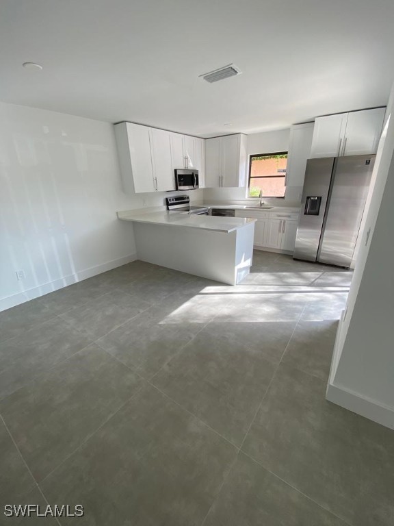 17989 San Juan Ct Unit 3, Fort Myers, FL 33967 - kitchen featuring stainless steel appliances, a peninsula, light countertops, and white cabinets