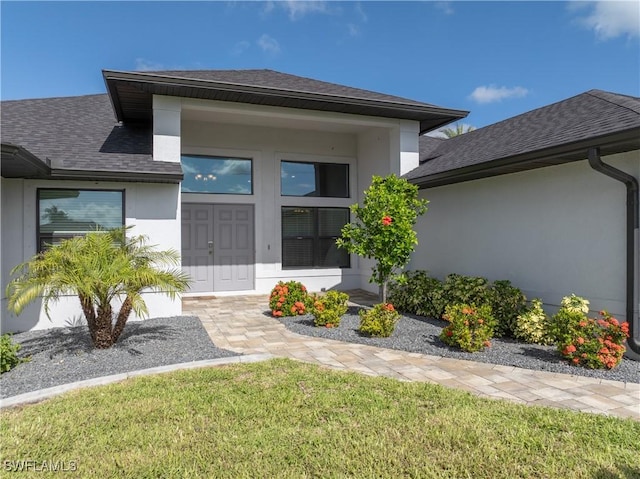 2502 SW 17th Ave, Cape Coral, FL 33914 - view of exterior entry with roof with shingles, stucco siding, and a yard