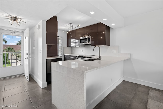 1666 Osprey Ave Unit 106, Naples, FL 34102 - kitchen with stainless steel microwave, a peninsula, recessed lighting, dark tile patterned floors, and light stone countertops