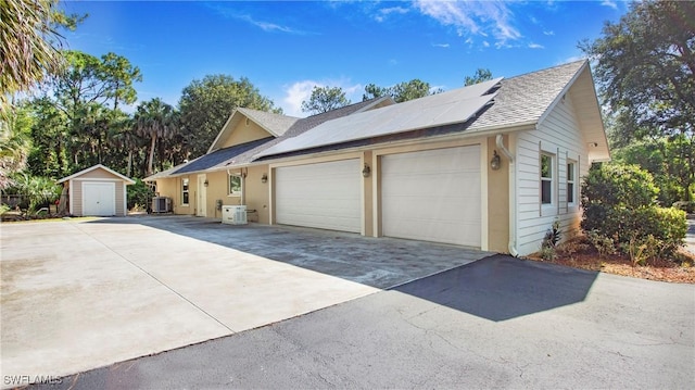 5961 Sea Grass Ln, Naples, FL 34116 - view of side of property with a shed, roof mounted solar panels, a detached garage, and roof with shingles