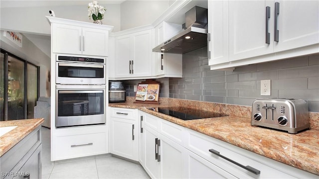 5961 Sea Grass Ln, Naples, FL 34116 - kitchen with wall chimney exhaust hood, double oven, black electric cooktop, white cabinets, and tasteful backsplash