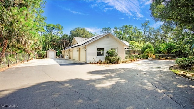 5961 Sea Grass Ln, Naples, FL 34116 - view of front of home with driveway, a garage, solar panels, and a storage unit