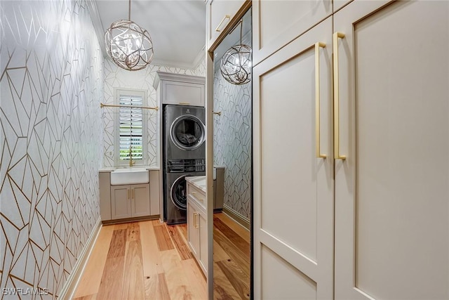 9691 Monteverdi Way, Fort Myers, FL 33912 - washroom with stacked washer / drying machine, wallpapered walls, cabinet space, light wood finished floors, and a chandelier