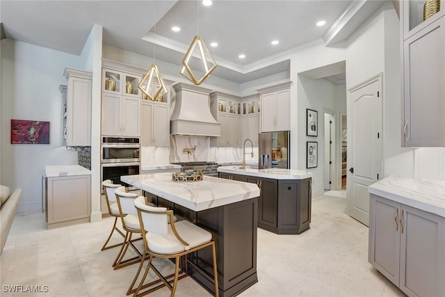 9691 Monteverdi Way, Fort Myers, FL 33912 - kitchen with a kitchen island with sink, custom range hood, stainless steel appliances, recessed lighting, and glass insert cabinets