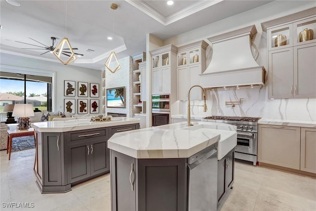 9691 Monteverdi Way, Fort Myers, FL 33912 - kitchen with a kitchen island with sink, a tray ceiling, appliances with stainless steel finishes, custom exhaust hood, and crown molding