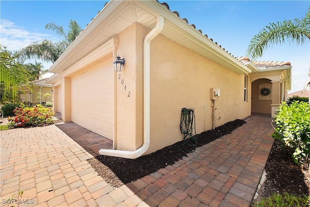 2042 Tamarron Ln, Naples, FL 34120 - view of home's exterior featuring stucco siding, a garage, a tile roof, and driveway