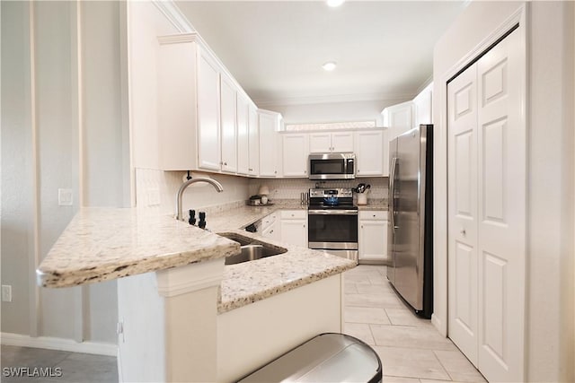 2042 Tamarron Ln, Naples, FL 34120 - kitchen featuring stainless steel appliances, a peninsula, light stone counters, light tile patterned floors, and white cabinetry