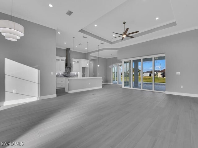 241 Rotonda Blvd S, Rotonda West, FL 33947 - unfurnished living room with a ceiling fan, a raised ceiling, ornamental molding, recessed lighting, and wood finished floors
