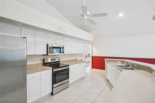13671 Willow Bridge Dr, North Fort Myers, FL 33903 - kitchen with stainless steel appliances, vaulted ceiling, white cabinets, light tile patterned floors, and light countertops