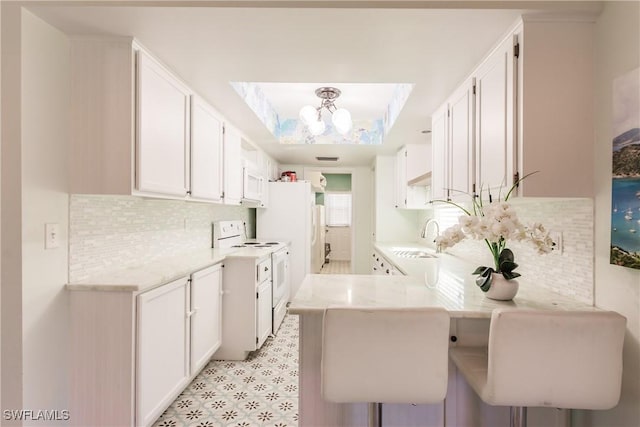 13611 Marquette Blvd, Fort Myers, FL 33905 - kitchen featuring white appliances, a peninsula, white cabinetry, and backsplash