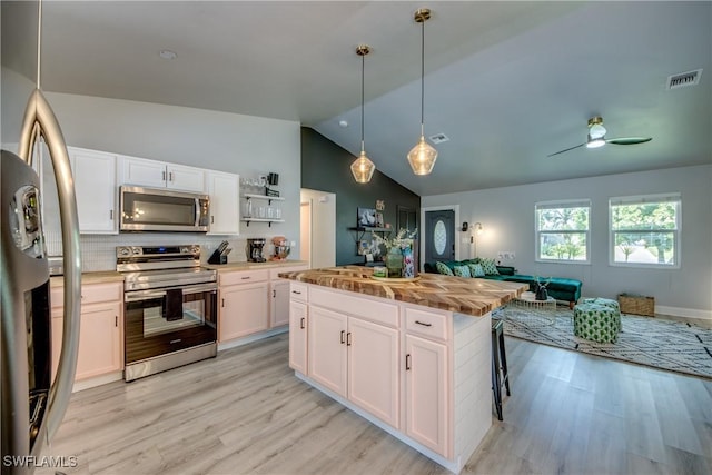 917 SW 23rd St, Cape Coral, FL 33991 - kitchen featuring appliances with stainless steel finishes, vaulted ceiling, open floor plan, light wood-style flooring, and white cabinets
